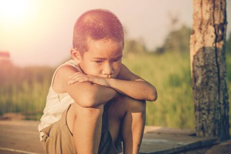 Little boy unhappy sitting alone on abandoned temporary housing.の写真素材