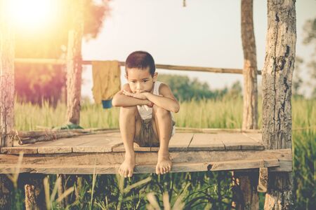 Little boy unhappy sitting alone on abandoned temporary housing.の写真素材