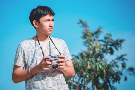 Lifestyle portrait of  young photographer with vintage camera taking photo.の写真素材
