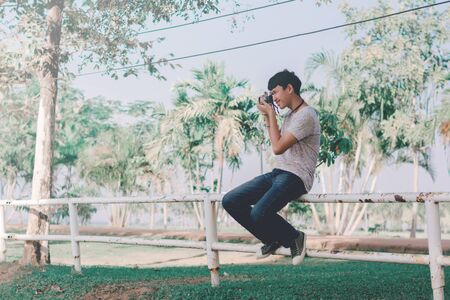 Lifestyle portrait of  young photographer with vintage camera taking photo.の写真素材