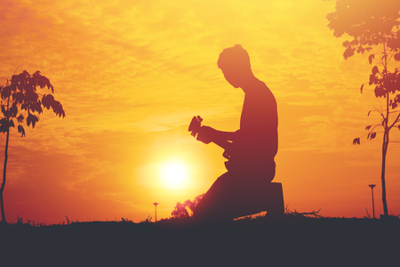 Silhouette of young musician holding a guitar on sunset.の写真素材