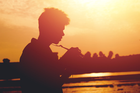 Silhouette of young photographer holding a camera on sunset.の写真素材