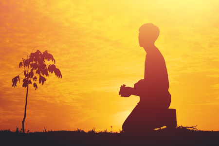 Silhouette of a young boy sitting sadly on sunset.の写真素材