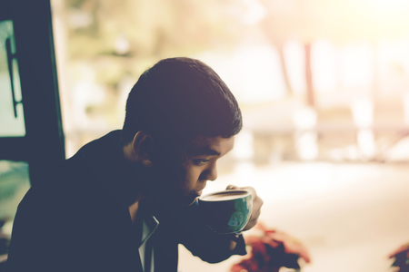 Young businessman looking to relax from work by sipping coffee.の写真素材