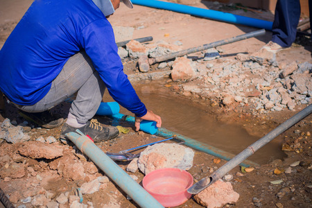 Construction worker,Repairing a broken water pipe on the concrete road.の写真素材