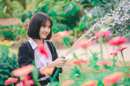 Girl student watering flower in the garden.の写真素材