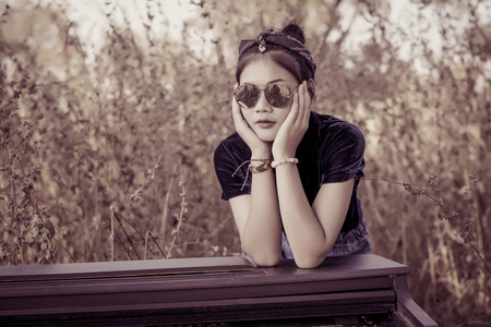 Fashion pretty young woman model in hipster style with vintage piano,fashion black glasses.の写真素材