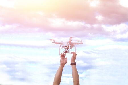 Man holding drone with hand outdoor and sunset sky background.