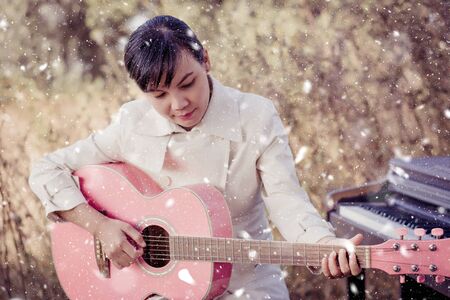 Beautiful woman playing guitar in the winter snow.
