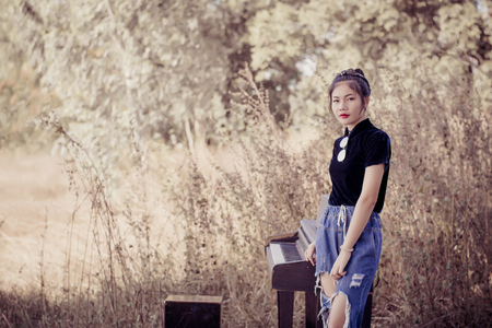 Fashion pretty young woman model in hipster style with piano ,fashion black glasses and vintage camera.の写真素材
