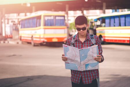 Young man handsome with luggage bag on city street with busy traffic transport looking map, waiting for public busの写真素材