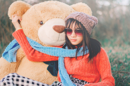 Hipster woman photography with a teddy bear in the winter on the park.の写真素材