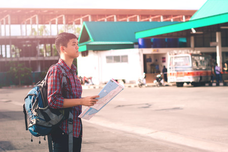 Young man handsome with luggage bag on city street with busy traffic transport looking map, waiting for public busの写真素材