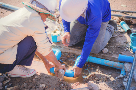 Construction worker,Repairing a broken water pipe on the concrete road.の写真素材