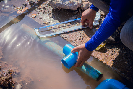 Construction worker,Repairing a broken water pipe on the concrete road.の写真素材