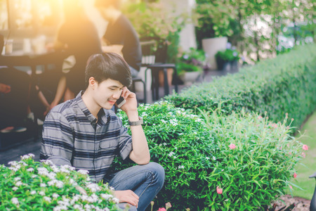 Young man talking on the smartphone in garden.の写真素材