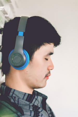 Young hipster gay man listening music headphones.