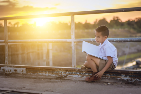 Boy student reading at the bridge at sunset,dream concept.の写真素材