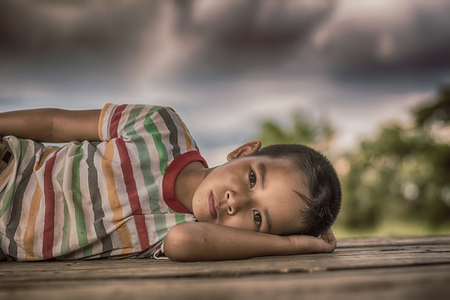 Little boy unhappy sleeping alone on abandoned temporary housing.の写真素材