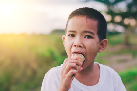 kid boy eating ice-cream outdoors before sunset.の写真素材