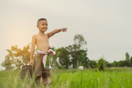 Asian boy to fish during the holidays in green farm field in summertime., Thailand.の写真素材