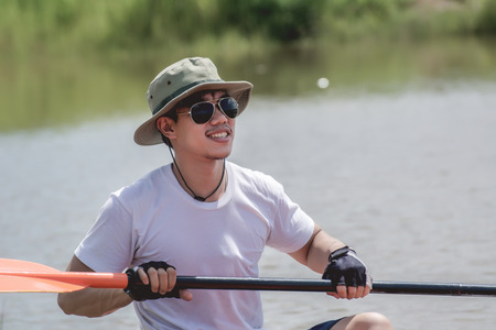 Fishing man with his boat on the river. He clutched a rowing paddle.の写真素材