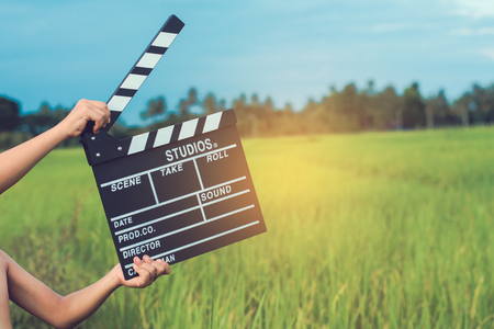 Kid playing film clapper board against summer sky background. Film director concept.の写真素材