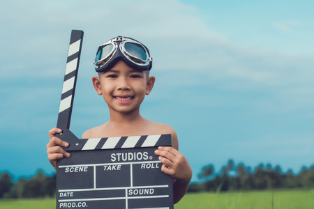 Kid playing film clapper board against summer sky background. Film director concept.の写真素材