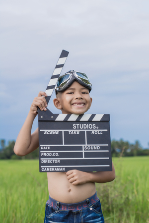 Kid playing film clapper board against summer sky background. Film director concept.の写真素材