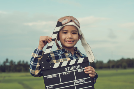 Kid playing film clapper board against summer sky background. Film director concept.の写真素材