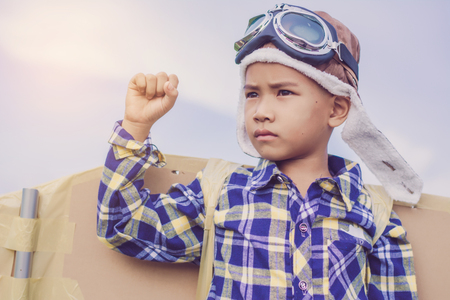 Child pretend to be pilot. Kid having fun at outdoor.He used paper to make wings. Summer vacation and travel concept.の写真素材