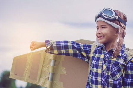 Child pretend to be pilot. Kid having fun at outdoor.He used paper to make wings. Summer vacation and travel concept.の写真素材
