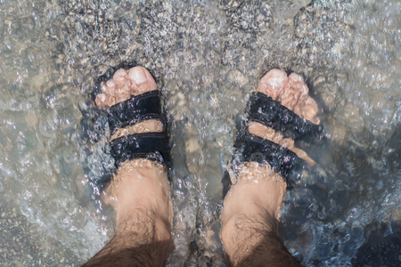 Young man feet in the water at the water fall.の写真素材