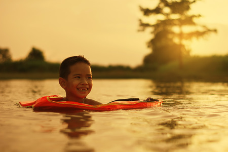 Kid playing water,happy time in the lake at sunset.の写真素材