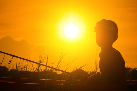 Silhouette of boy catch fish from a boat at sunset,a happy time for the holidays.