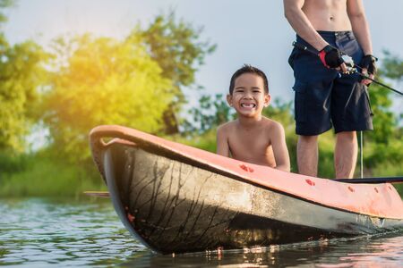 Son and father catch fish from a boat at sunset,a happy time for the holidays.の写真素材