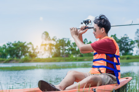 fishing man on board into the river against the background of a picturesque landscape at dawn, on sunset.の写真素材