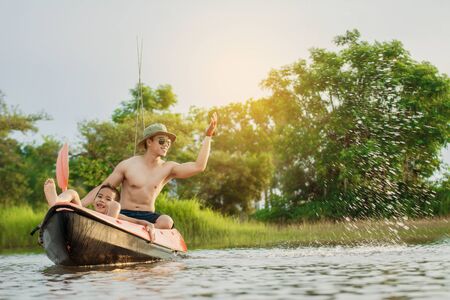 Son and father catch fish from a boat at sunset,a happy time for the holidays.の写真素材