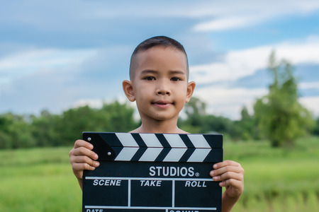 Kid playing film clapper board against summer sky background. Film director concept.のeditorial素材