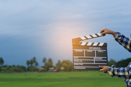 Kid playing film clapper board against summer sky background. Film director concept.の写真素材