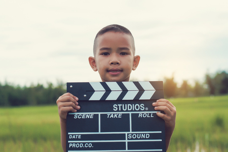 Kid playing film clapper board against summer sky background. Film director concept.の写真素材