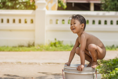 Children play and bathed water in the garden,sitting in a bucket of water. Concept of raising childrenの写真素材