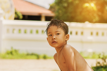 Children play and bathed water in the garden,sitting in a bucket of water. Concept of raising children.の写真素材