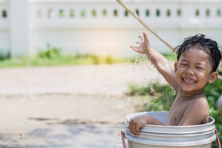 Children play and bathed water in the garden,sitting in a bucket of water. Concept of raising children.の写真素材