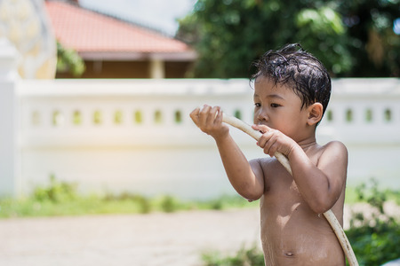 Children play and bathed water in the garden,sitting in a bucket of water. Concept of raising children.の写真素材