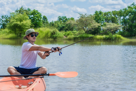 Young man fishing during in The River, He sitting on his boat. Man Relaxing During Vacation.の写真素材