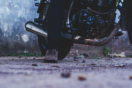 Handsome young men with black color classic motobike(motorcycle) on cement background.の写真素材