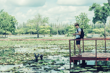 Young man tourists shooting vintage camera and backpack, shooting style, travel style in the park.の写真素材