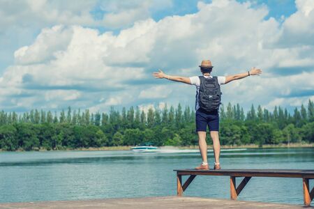 Young man tourists looking at the boat and waving on the pier,travel style.の写真素材