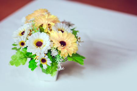 Plastic flowers with vases on the table with white cloth as the floor.の写真素材